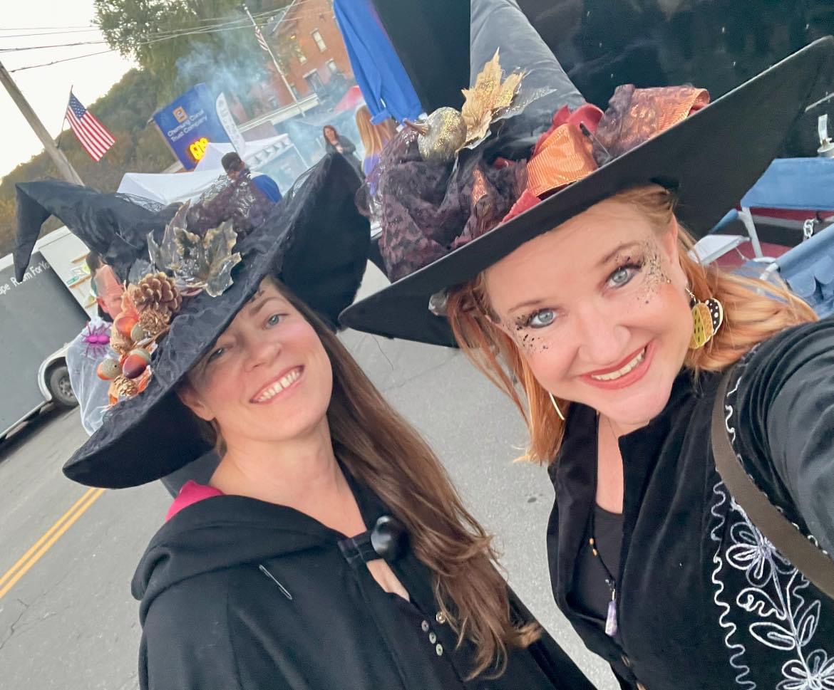 Stephanie and Tera in festive witch hats at a local event